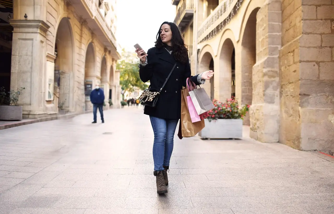 A woman checking her phone on a shopping street